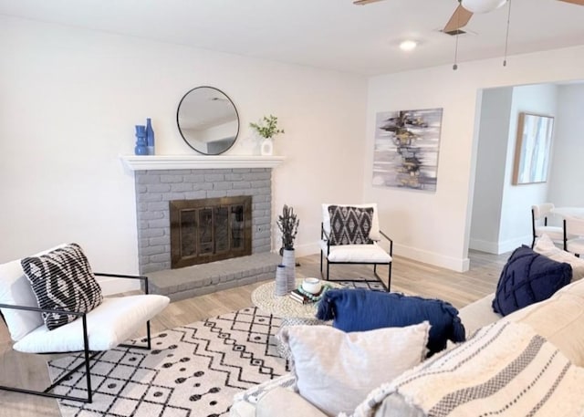 living room with ceiling fan, a fireplace, and light hardwood / wood-style floors