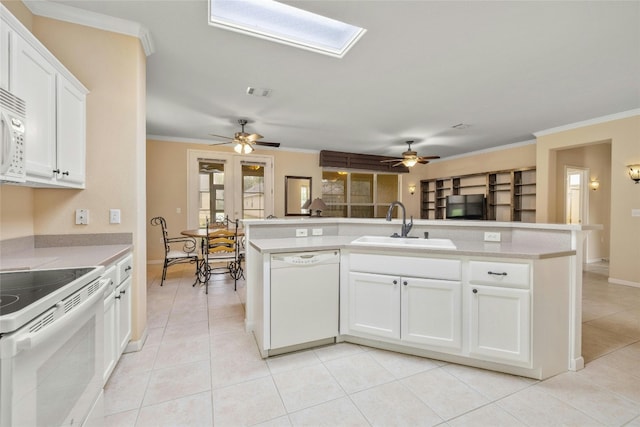 kitchen with white cabinets, light tile patterned floors, a skylight, crown molding, and white appliances