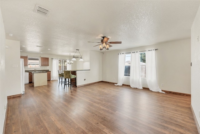 unfurnished living room featuring dark wood-type flooring, a textured ceiling, and a wealth of natural light