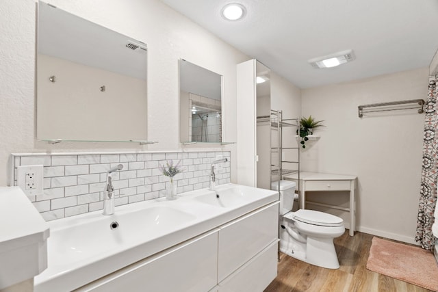 bathroom featuring toilet, backsplash, hardwood / wood-style floors, vanity, and walk in shower