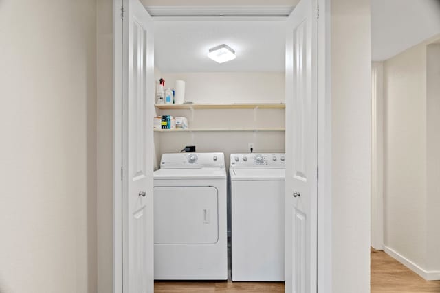 clothes washing area with light hardwood / wood-style flooring and washer and clothes dryer