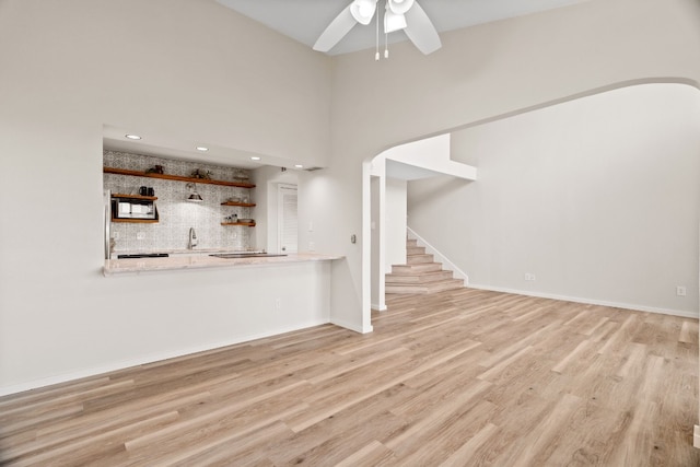 unfurnished living room with sink, light hardwood / wood-style flooring, and ceiling fan