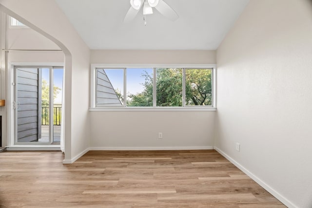 spare room with a wealth of natural light, lofted ceiling, light wood-type flooring, and ceiling fan