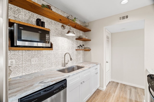 kitchen featuring stainless steel appliances, backsplash, sink, light wood-type flooring, and white cabinetry