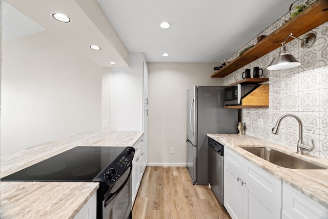 kitchen featuring tasteful backsplash, appliances with stainless steel finishes, white cabinetry, light wood-type flooring, and sink