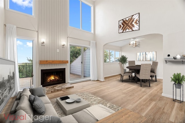 living room featuring a towering ceiling, light wood-type flooring, and a fireplace