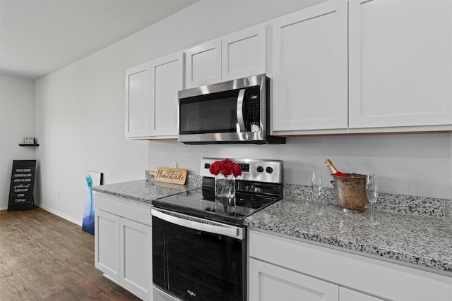 11104 Roving Pass, Elgin, TX 78621 - kitchen featuring light stone countertops, baseboards, white cabinetry, dark wood-type flooring, and stainless steel appliances
