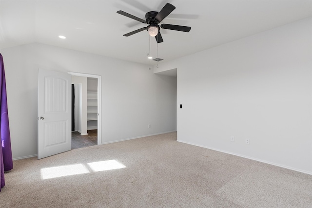 unfurnished bedroom featuring carpet flooring, a walk in closet, a closet, ceiling fan, and vaulted ceiling