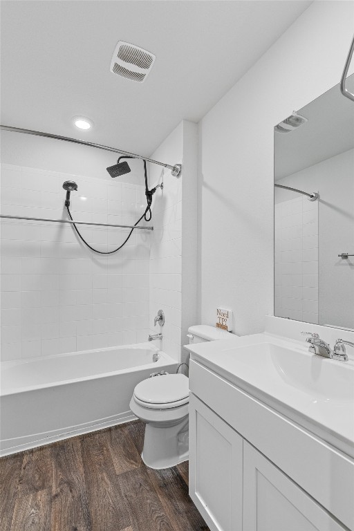 full bathroom featuring toilet, tiled shower / bath, hardwood / wood-style floors, and vanity