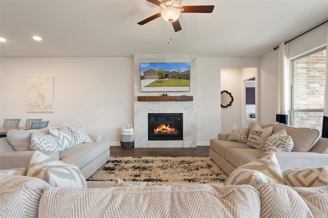 living room with wood-type flooring, ceiling fan, and a fireplace