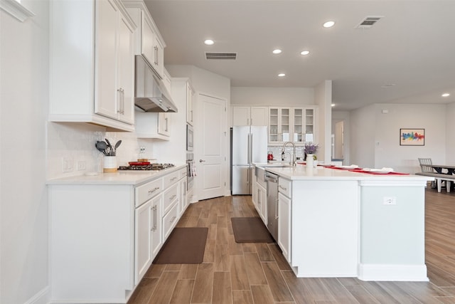 kitchen with stainless steel appliances, an island with sink, and white cabinets