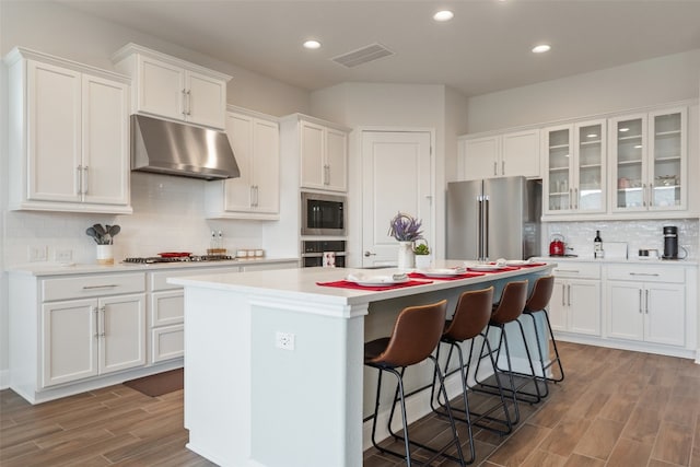 kitchen featuring white cabinetry, a kitchen bar, a center island, and stainless steel appliances