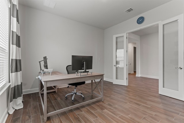 office with french doors, hardwood / wood-style flooring, and a healthy amount of sunlight