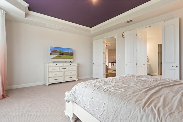 carpeted bedroom featuring ensuite bathroom and a tray ceiling