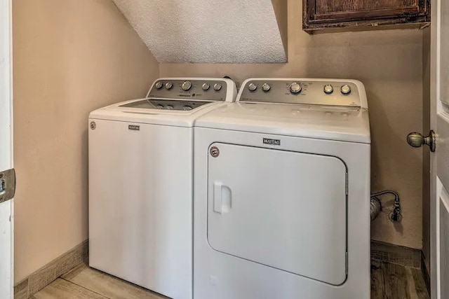 washroom featuring a textured ceiling, separate washer and dryer, and light tile patterned floors