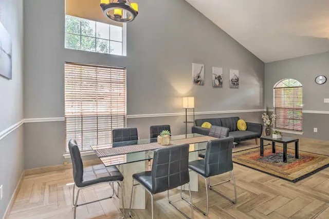 dining space featuring a healthy amount of sunlight, light parquet floors, high vaulted ceiling, and a notable chandelier