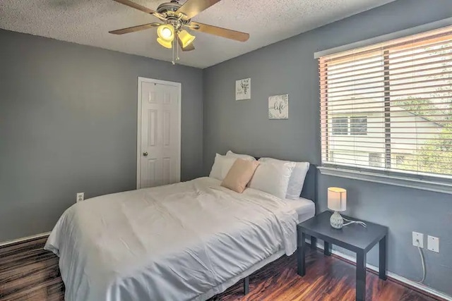 bedroom with a textured ceiling, dark wood-type flooring, and ceiling fan