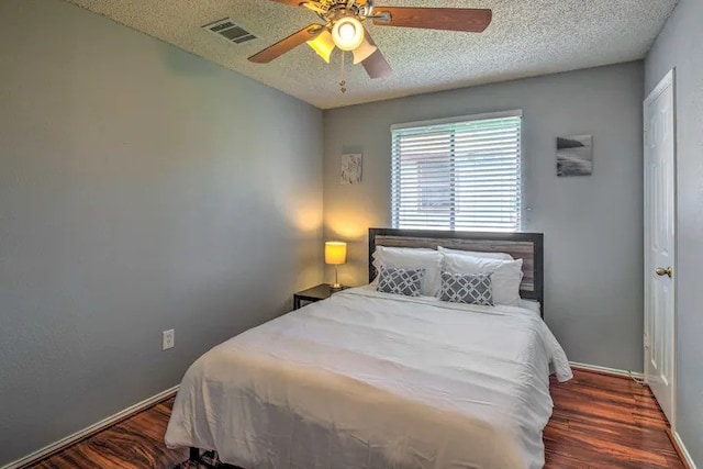 bedroom featuring ceiling fan, a textured ceiling, and dark hardwood / wood-style flooring