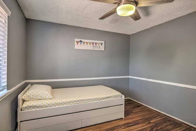 bedroom with multiple windows, a textured ceiling, dark wood-type flooring, and ceiling fan