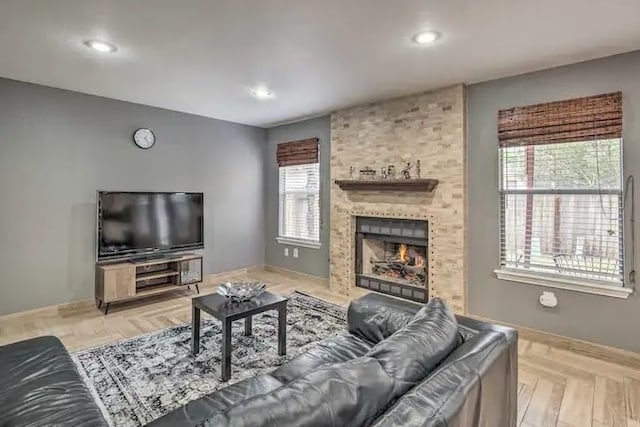 living room featuring a large fireplace, light hardwood / wood-style flooring, and a healthy amount of sunlight