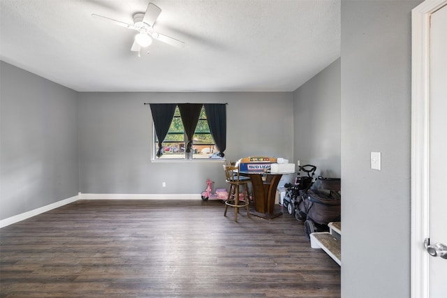 rec room featuring a textured ceiling, dark wood-type flooring, and ceiling fan