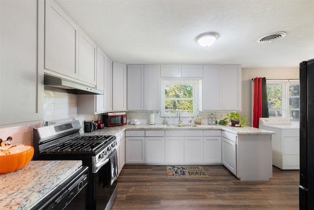 kitchen with stainless steel gas stove, washer / clothes dryer, a wealth of natural light, and white cabinets