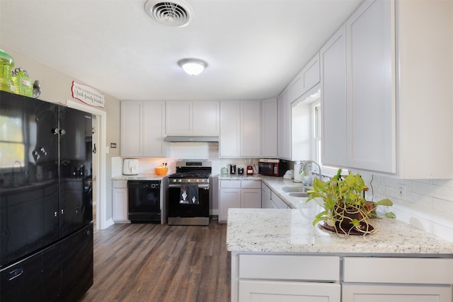 kitchen with light stone countertops, sink, dark hardwood / wood-style flooring, stainless steel range with gas stovetop, and white cabinets