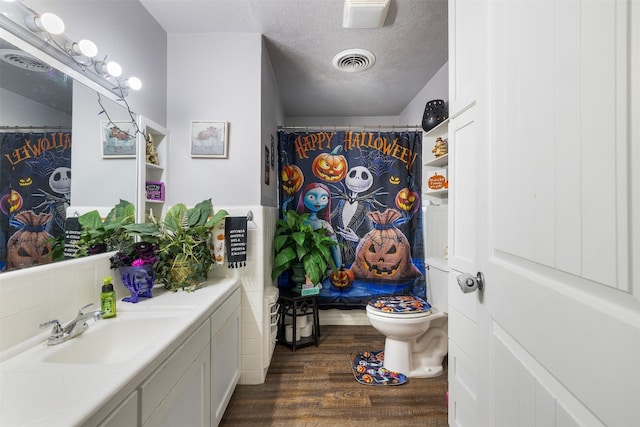 bathroom with a textured ceiling, hardwood / wood-style floors, toilet, a shower with curtain, and vanity