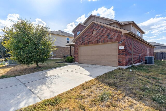 view of front of home featuring a front yard, central AC, and a garage