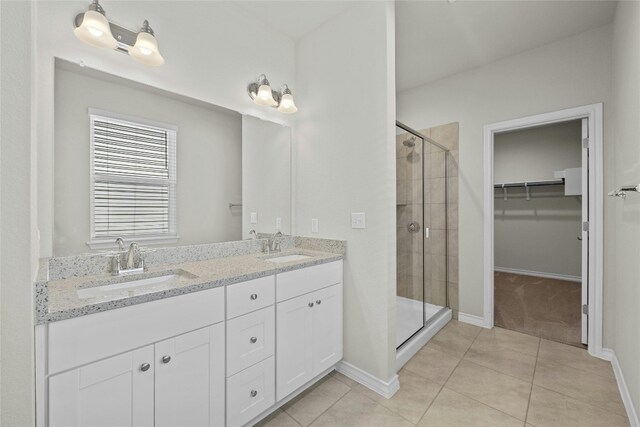 bathroom with a shower with door, vanity, and tile patterned flooring