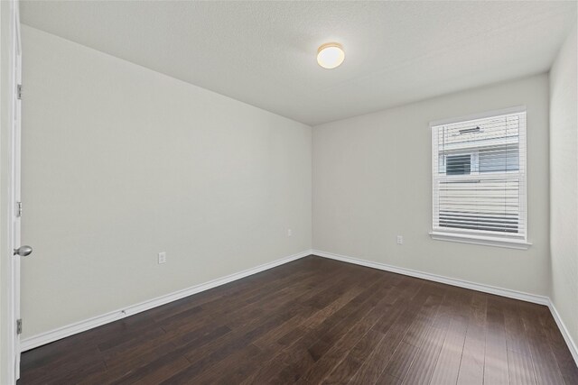 unfurnished room with a textured ceiling and dark hardwood / wood-style floors