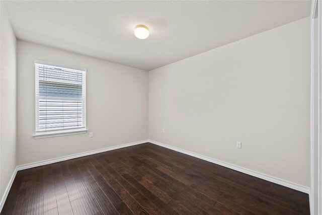 spare room featuring a textured ceiling and dark hardwood / wood-style floors