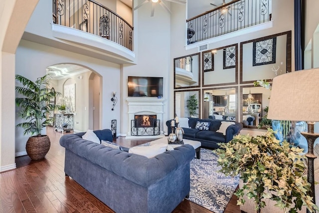 living room featuring a high ceiling, dark hardwood / wood-style flooring, and ceiling fan