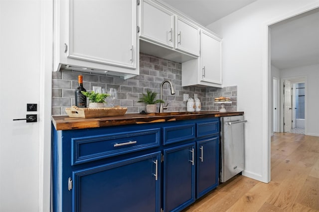 kitchen with wood counters, sink, light wood-type flooring, blue cabinetry, and white cabinetry