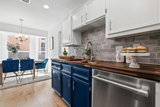 kitchen featuring stainless steel dishwasher, blue cabinets, butcher block counters, and white cabinets