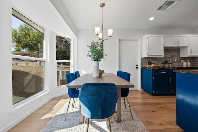 dining space featuring sink, light hardwood / wood-style flooring, and an inviting chandelier