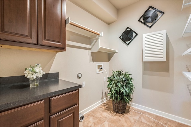 laundry area featuring hookup for a washing machine, light tile patterned flooring, and cabinets