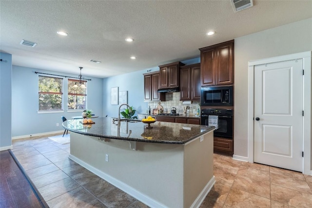 kitchen featuring black appliances, a center island with sink, sink, dark stone countertops, and a textured ceiling