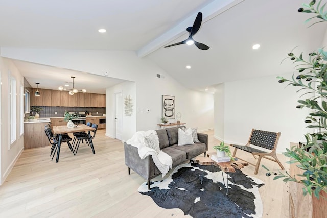 living room featuring vaulted ceiling with beams, ceiling fan with notable chandelier, and light hardwood / wood-style flooring