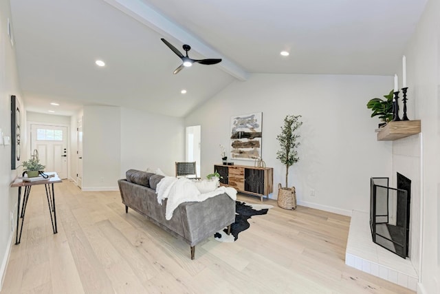 living room with lofted ceiling with beams, ceiling fan, a fireplace, and light hardwood / wood-style flooring