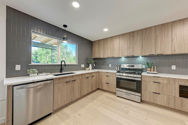 kitchen featuring sink, light brown cabinets, hanging light fixtures, light hardwood / wood-style floors, and appliances with stainless steel finishes