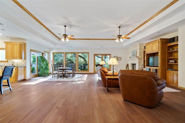 living room featuring ceiling fan, a tray ceiling, and light hardwood / wood-style floors