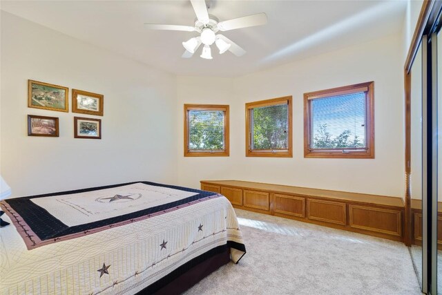 carpeted bedroom with ceiling fan and a closet