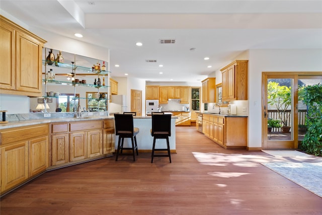 kitchen featuring light wood-type flooring, sink, a breakfast bar, and white appliances