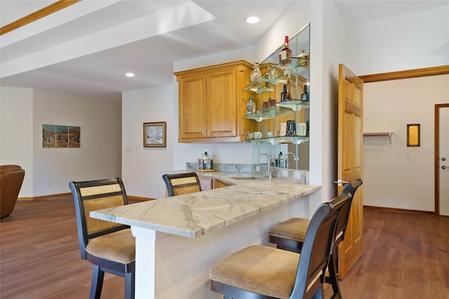 kitchen featuring a kitchen breakfast bar, light stone countertops, dark wood-type flooring, and sink