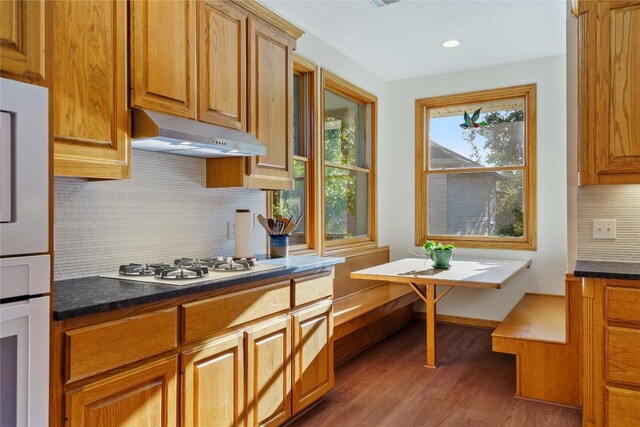 kitchen with dark wood-type flooring, a wealth of natural light, backsplash, and white appliances