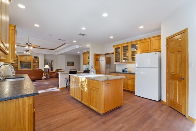 kitchen featuring ceiling fan, a center island, sink, light hardwood / wood-style flooring, and white refrigerator