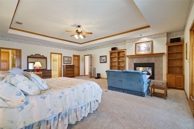 bedroom with light carpet, ceiling fan, a raised ceiling, crown molding, and a tile fireplace