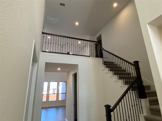 stairway featuring a towering ceiling