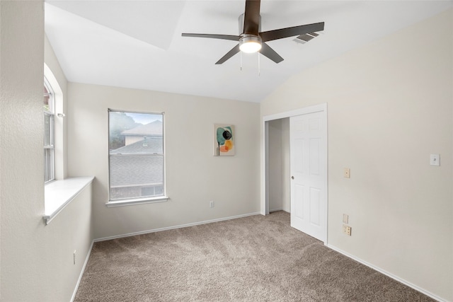 unfurnished bedroom with vaulted ceiling, light colored carpet, a closet, and ceiling fan